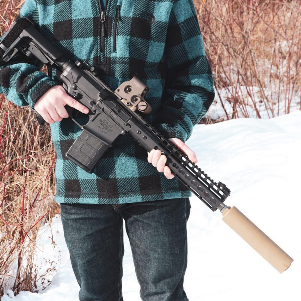 A person holding a 8.6 Blackout pistol with a suppressor
